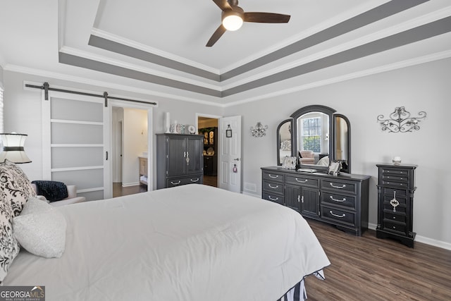 bedroom featuring a barn door, dark wood-type flooring, baseboards, ornamental molding, and a raised ceiling