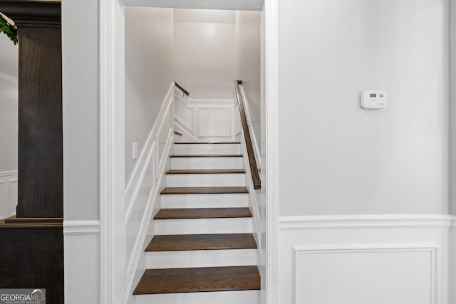 stairway featuring a wainscoted wall and a decorative wall