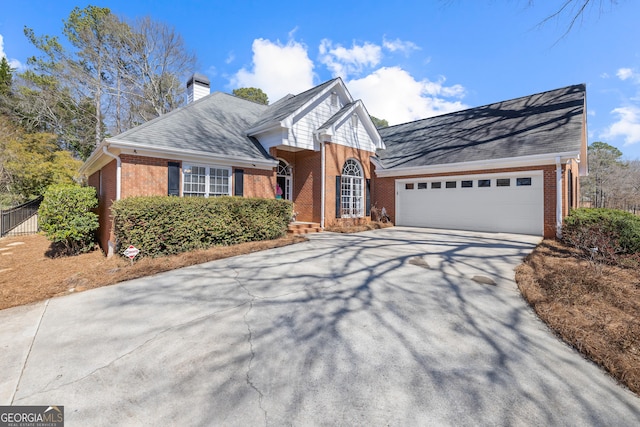 view of front of property featuring a garage, brick siding, a shingled roof, driveway, and a chimney