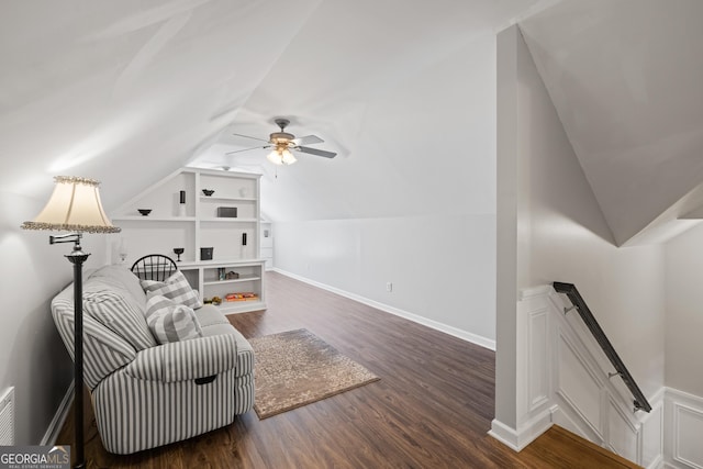 sitting room with wood finished floors, a ceiling fan, built in features, vaulted ceiling, and baseboards