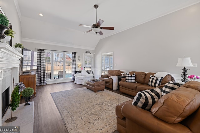 living area with lofted ceiling, ceiling fan, ornamental molding, wood finished floors, and a fireplace