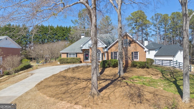 view of front of home featuring a chimney, fence, and brick siding