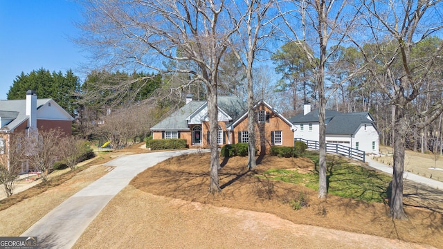 traditional home featuring concrete driveway, brick siding, and fence