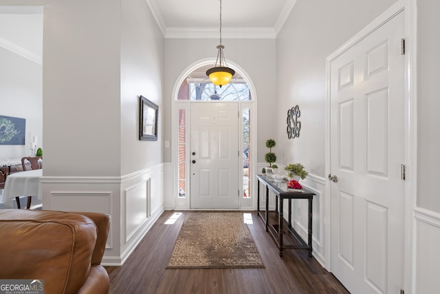 foyer with a wainscoted wall, a decorative wall, dark wood finished floors, and crown molding