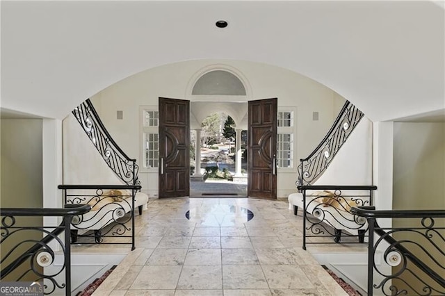 entrance foyer featuring lofted ceiling, stairway, and arched walkways