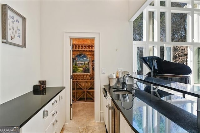 kitchen featuring dark countertops, white cabinetry, and a sink