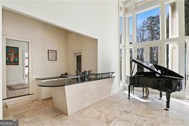 living area featuring a towering ceiling and baseboards