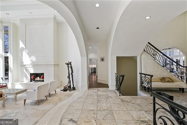 entryway with recessed lighting, arched walkways, baseboards, and a multi sided fireplace