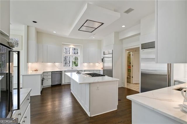 kitchen featuring light stone countertops, appliances with stainless steel finishes, decorative backsplash, and dark wood-type flooring