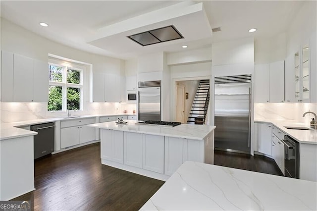 kitchen with stainless steel appliances, light stone counters, a sink, and decorative backsplash