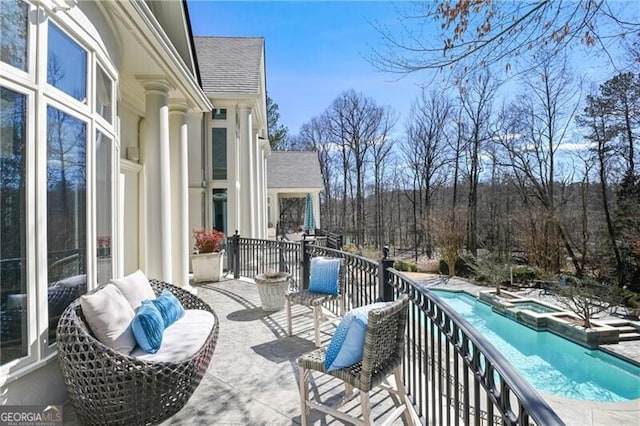 balcony with a patio area, an outdoor hangout area, and an in ground hot tub