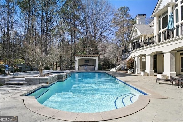 outdoor pool featuring a patio area and an outdoor fireplace