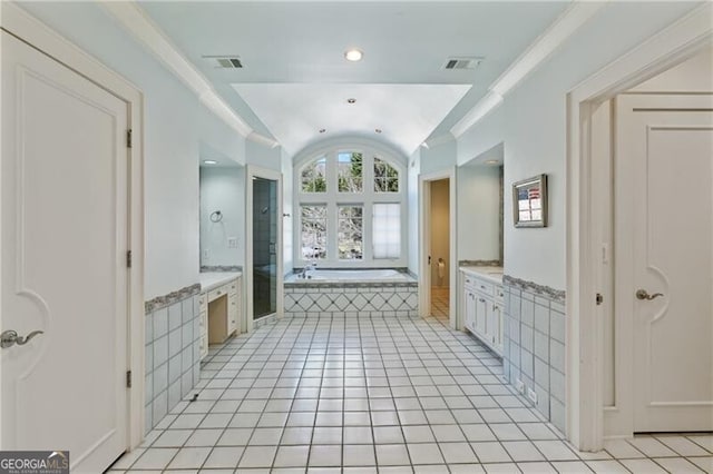 full bathroom featuring a garden tub, lofted ceiling, visible vents, vanity, and tile patterned floors