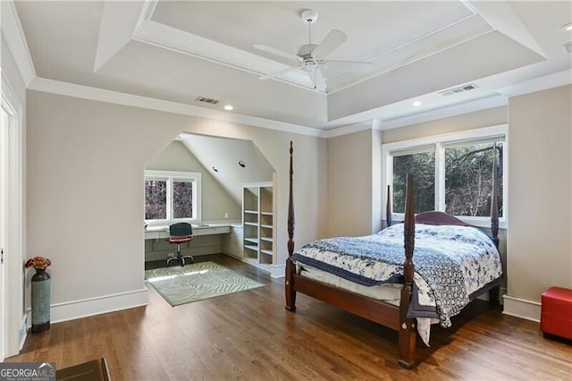 bedroom with a tray ceiling and wood finished floors