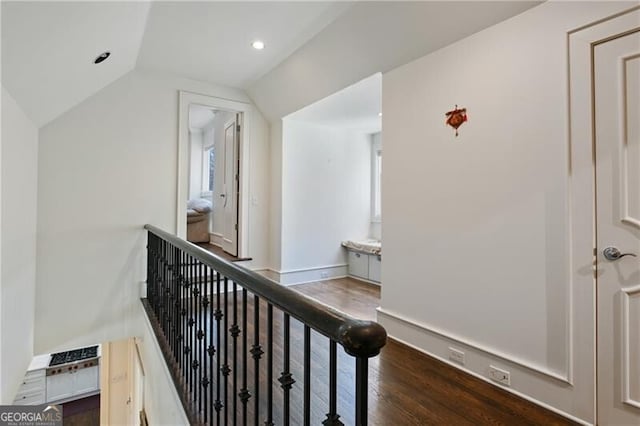 corridor featuring recessed lighting, vaulted ceiling, wood finished floors, and an upstairs landing