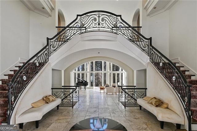 foyer entrance with arched walkways, marble finish floor, a high ceiling, and stairs