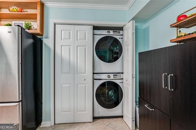 laundry room with stacked washer and dryer, laundry area, crown molding, and light tile patterned floors