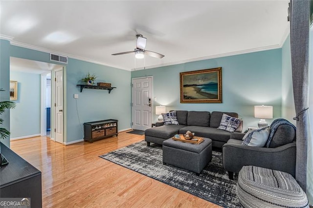 living room featuring ceiling fan, wood finished floors, visible vents, baseboards, and ornamental molding