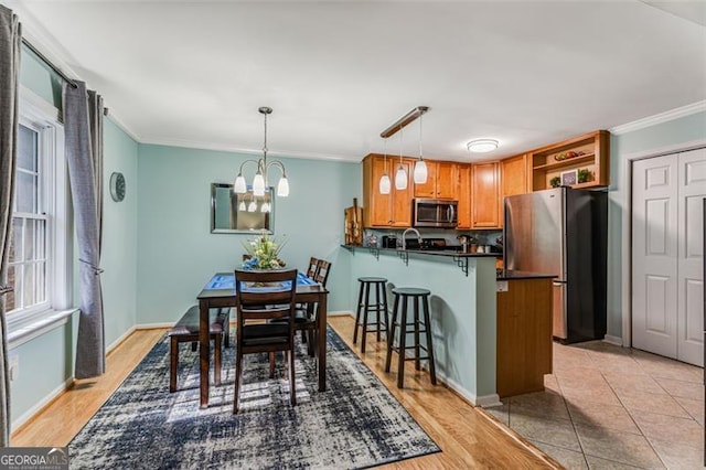 dining space featuring a chandelier, light tile patterned floors, baseboards, and crown molding