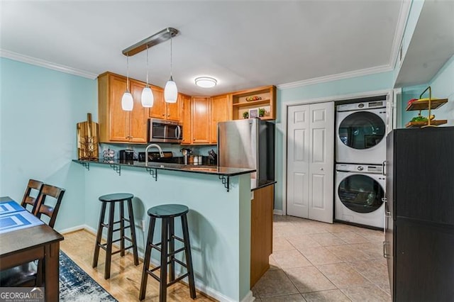 kitchen with appliances with stainless steel finishes, dark countertops, pendant lighting, and a breakfast bar area