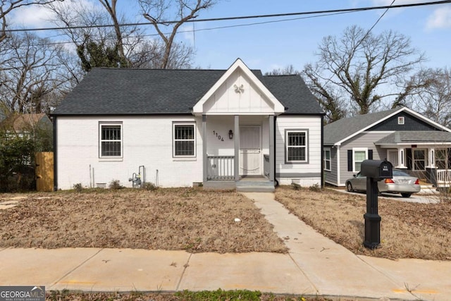 bungalow with brick siding and roof with shingles