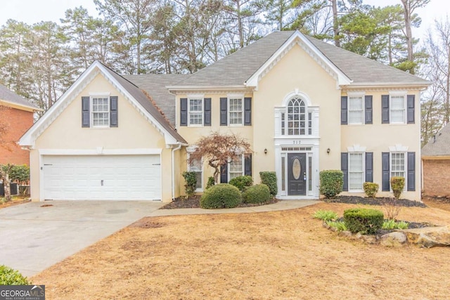 colonial home featuring a garage, concrete driveway, and stucco siding