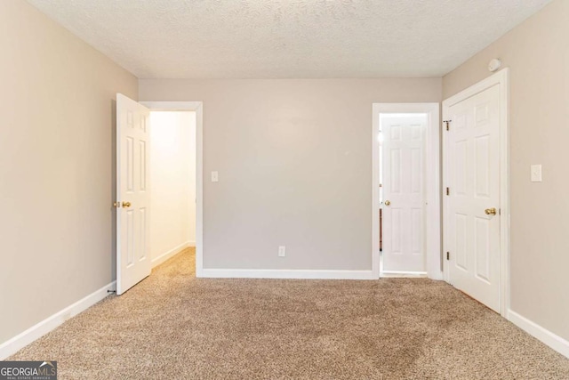 unfurnished bedroom featuring a textured ceiling, carpet flooring, and baseboards