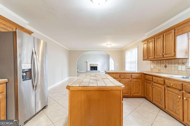 kitchen with a center island, tile countertops, light tile patterned floors, open floor plan, and stainless steel fridge