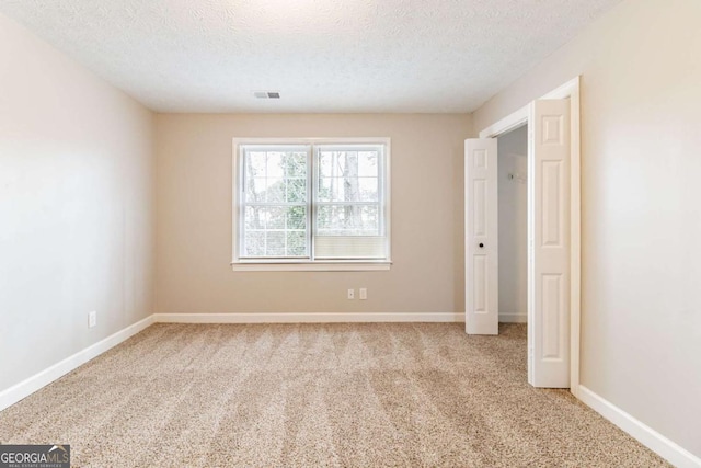 unfurnished bedroom with visible vents, light carpet, baseboards, and a textured ceiling