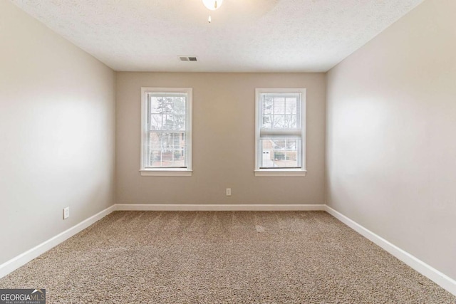 spare room with plenty of natural light, carpet flooring, visible vents, and baseboards