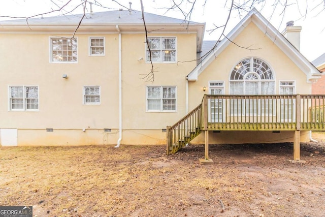 rear view of house featuring a deck, stairway, crawl space, stucco siding, and a chimney