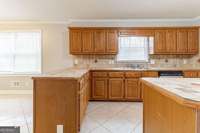 kitchen featuring brown cabinetry, a sink, stainless steel dishwasher, and light tile patterned floors