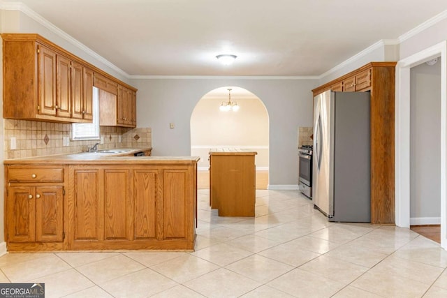 kitchen with arched walkways, light countertops, appliances with stainless steel finishes, a kitchen island, and a peninsula