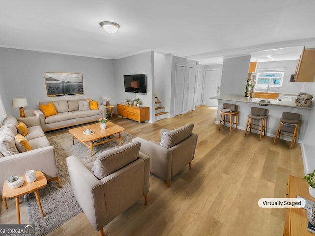 living room featuring light wood-style flooring, stairs, and ornamental molding