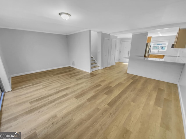 unfurnished living room with ornamental molding, light wood-type flooring, stairway, and baseboards