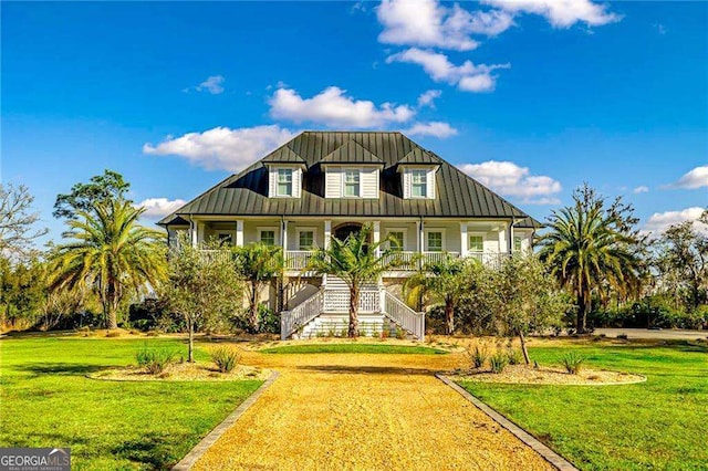 beach home featuring stairway, metal roof, a standing seam roof, covered porch, and a front yard