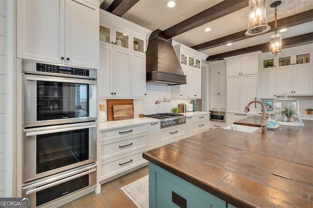 kitchen featuring a sink, appliances with stainless steel finishes, custom exhaust hood, and white cabinets