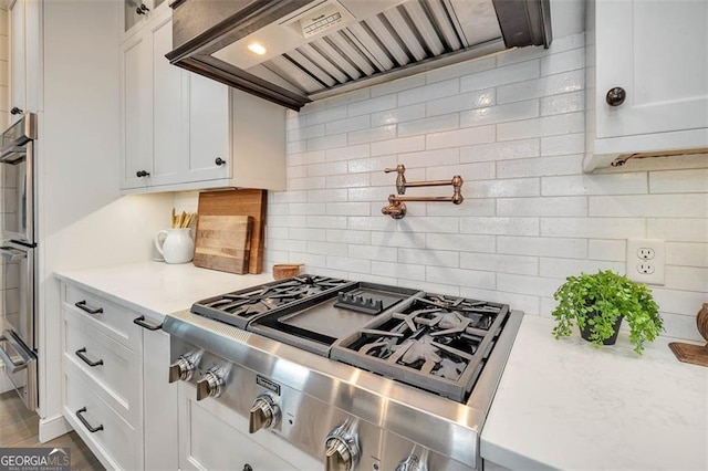 kitchen featuring white cabinetry, stainless steel gas cooktop, backsplash, and custom exhaust hood