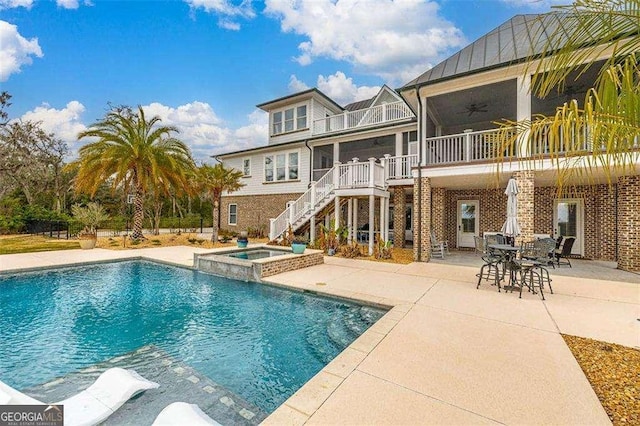 back of property with ceiling fan, a patio, a balcony, brick siding, and stairway