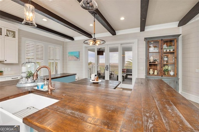 kitchen featuring wood walls, butcher block counters, pendant lighting, and a sink