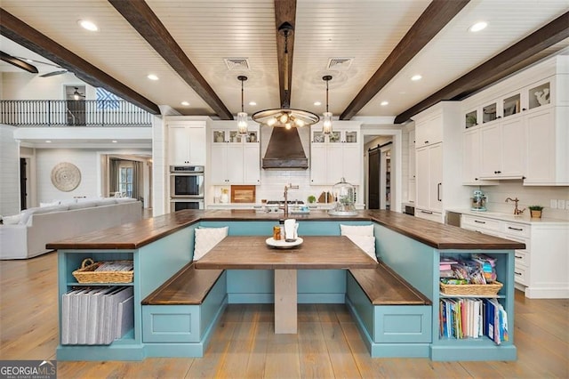 kitchen featuring butcher block counters, open shelves, premium range hood, and a barn door