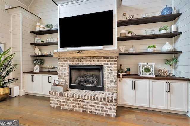 bar with wooden walls, a fireplace, and hardwood / wood-style floors