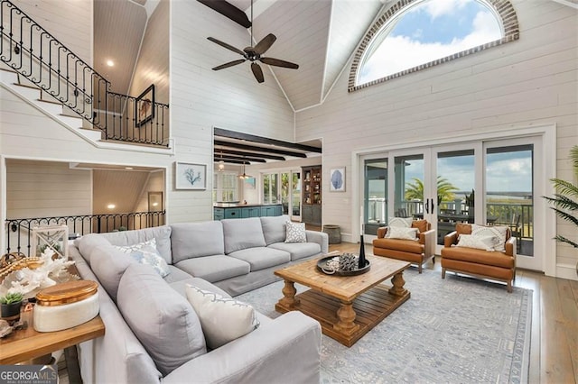 living area featuring high vaulted ceiling, hardwood / wood-style floors, wood walls, and plenty of natural light