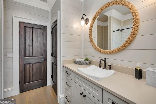 bathroom featuring wood walls, vanity, and wood finished floors