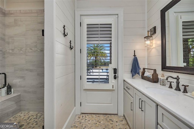 bathroom with wood walls, a shower stall, and vanity