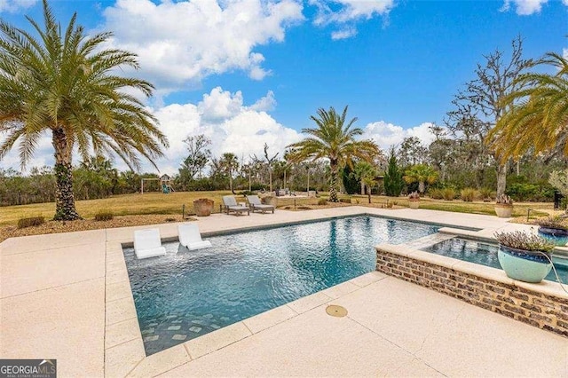 pool with a patio, a lawn, and an in ground hot tub