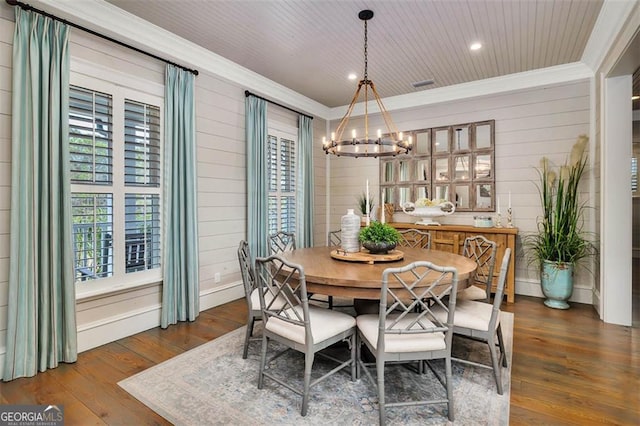 dining area featuring crown molding, wood walls, a chandelier, wooden ceiling, and hardwood / wood-style floors