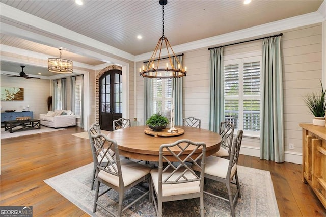 dining area featuring plenty of natural light, wood-type flooring, arched walkways, and crown molding