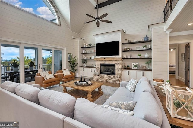 living room with ceiling fan, high vaulted ceiling, a fireplace, wood finished floors, and ornate columns