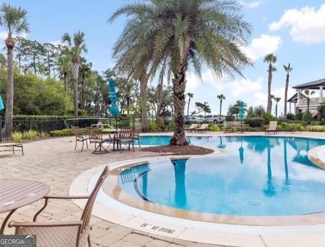 community pool with a patio area and fence